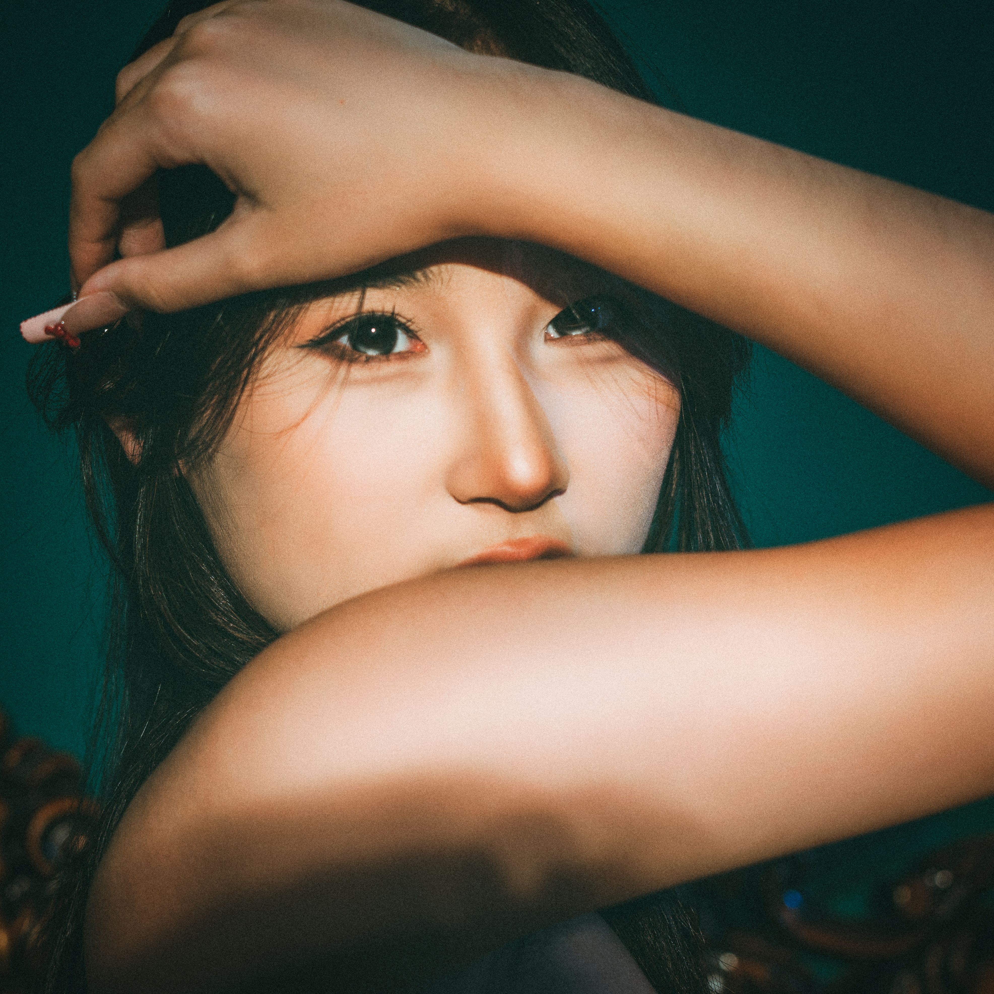 Close-up portrait of a woman with arm raised, creating a mysterious and dramatic mood.