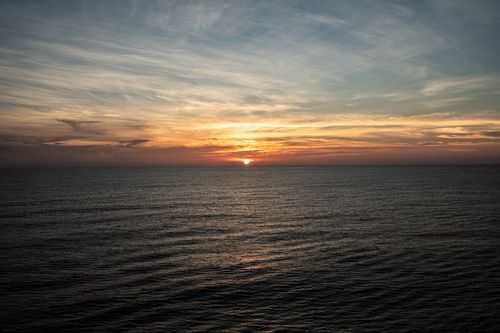 Free Beautiful sunset over the ocean with vibrant sky colors and peaceful water reflections. Stock Photo