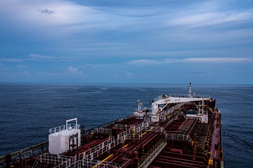 Free Aerial view of a large cargo ship on a calm ocean under a cloudy blue sky. Stock Photo