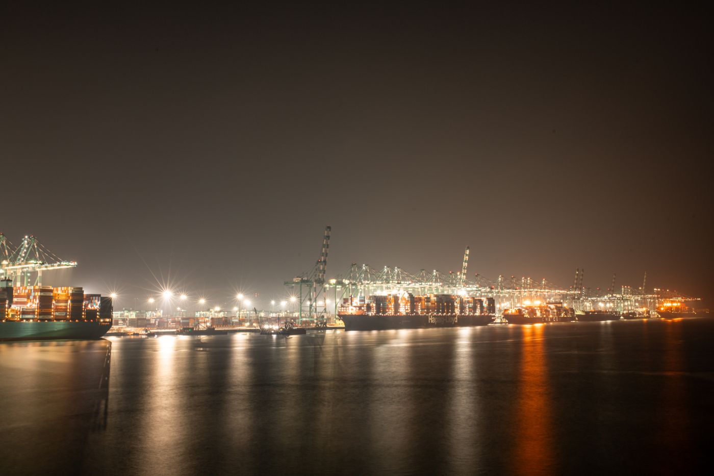 Container port at night with cranes and stacked containers