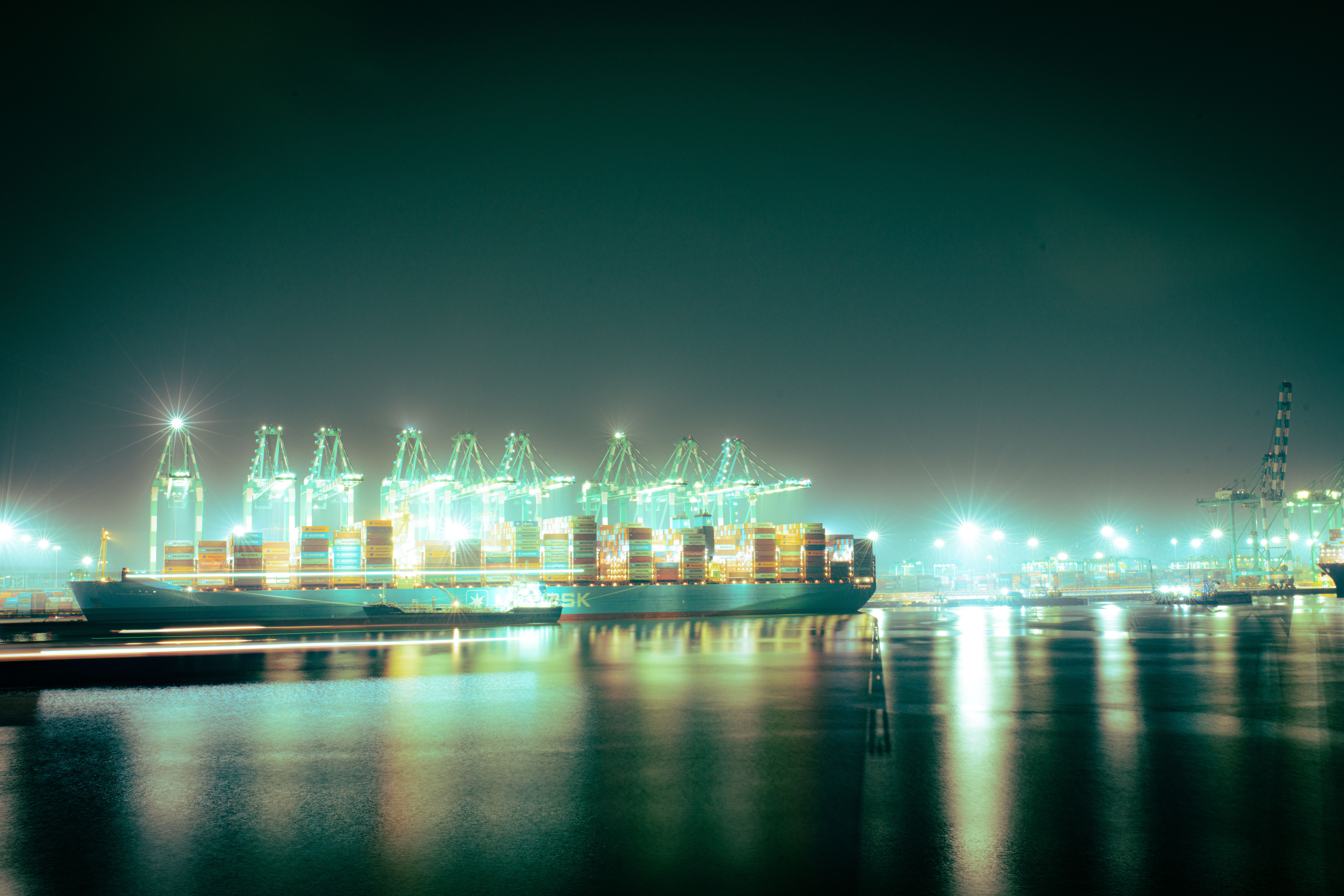 Container ship and cranes at a brightly lit international port at night