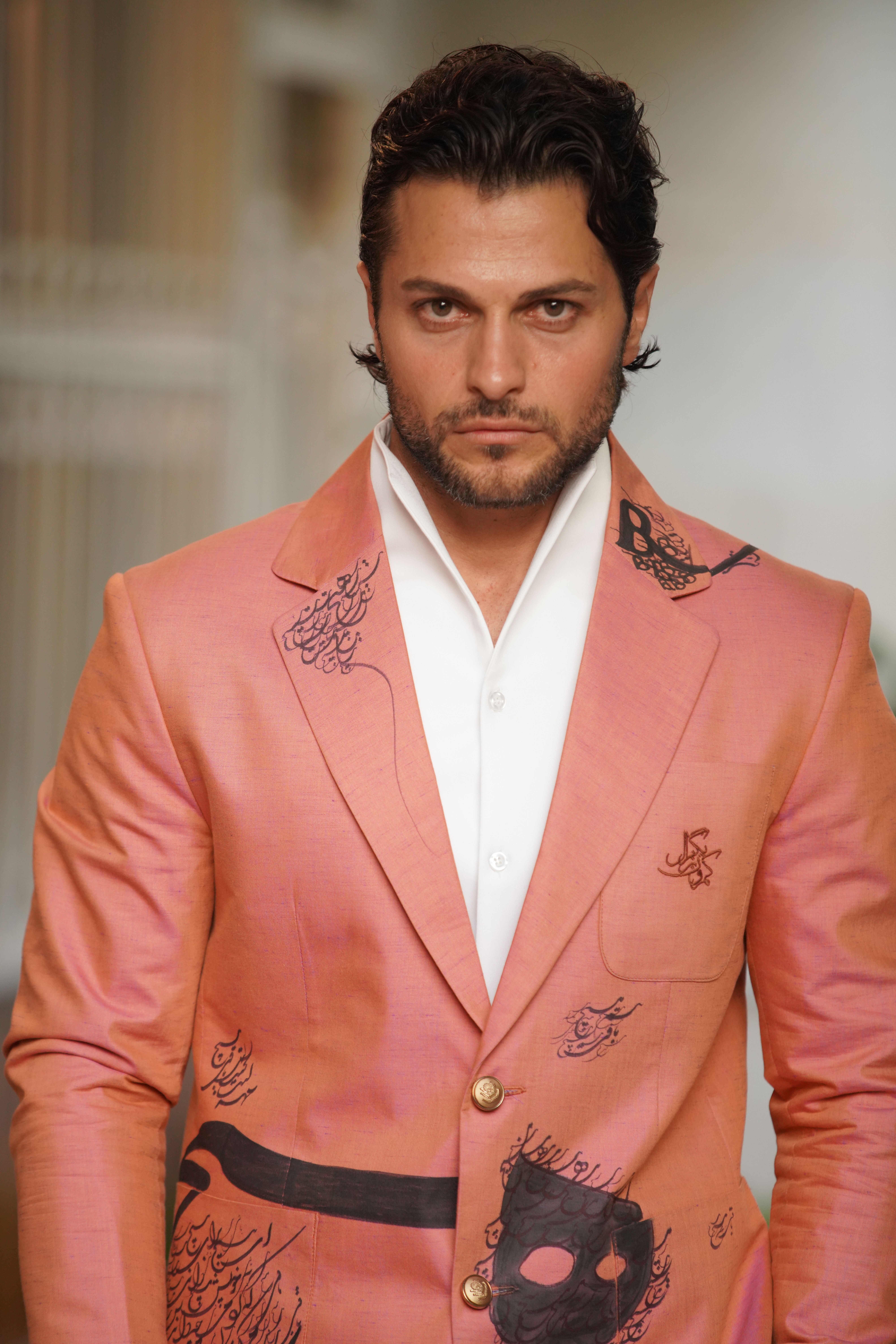 Portrait of a confident man in a unique pink suit with artistic patterns, indoors.
