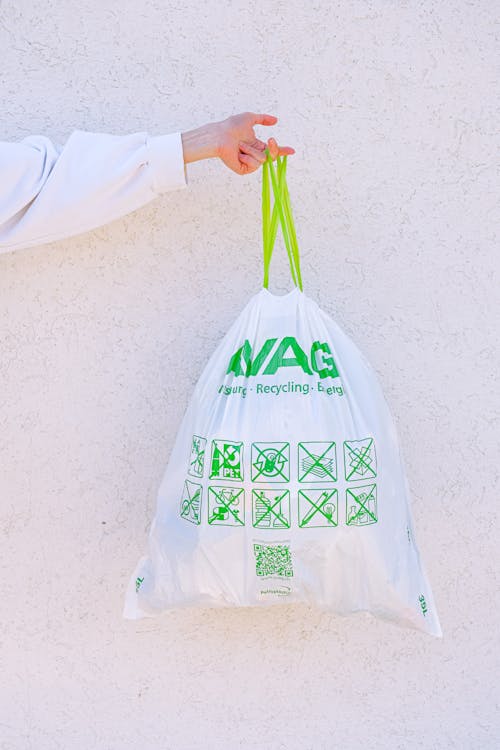 Person Holding White and Green Plastic Bag