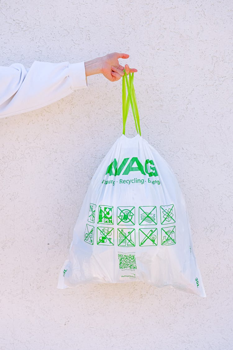 Person Holding White And Green Plastic Bag