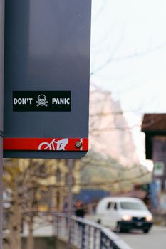 城市环境中，一个带有“不要恐慌”信息和车辆、自行车符号的标志特写