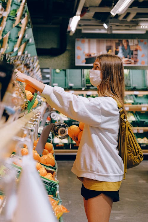 Woman in White Long Sleeve Jacket Shopping For Fruits