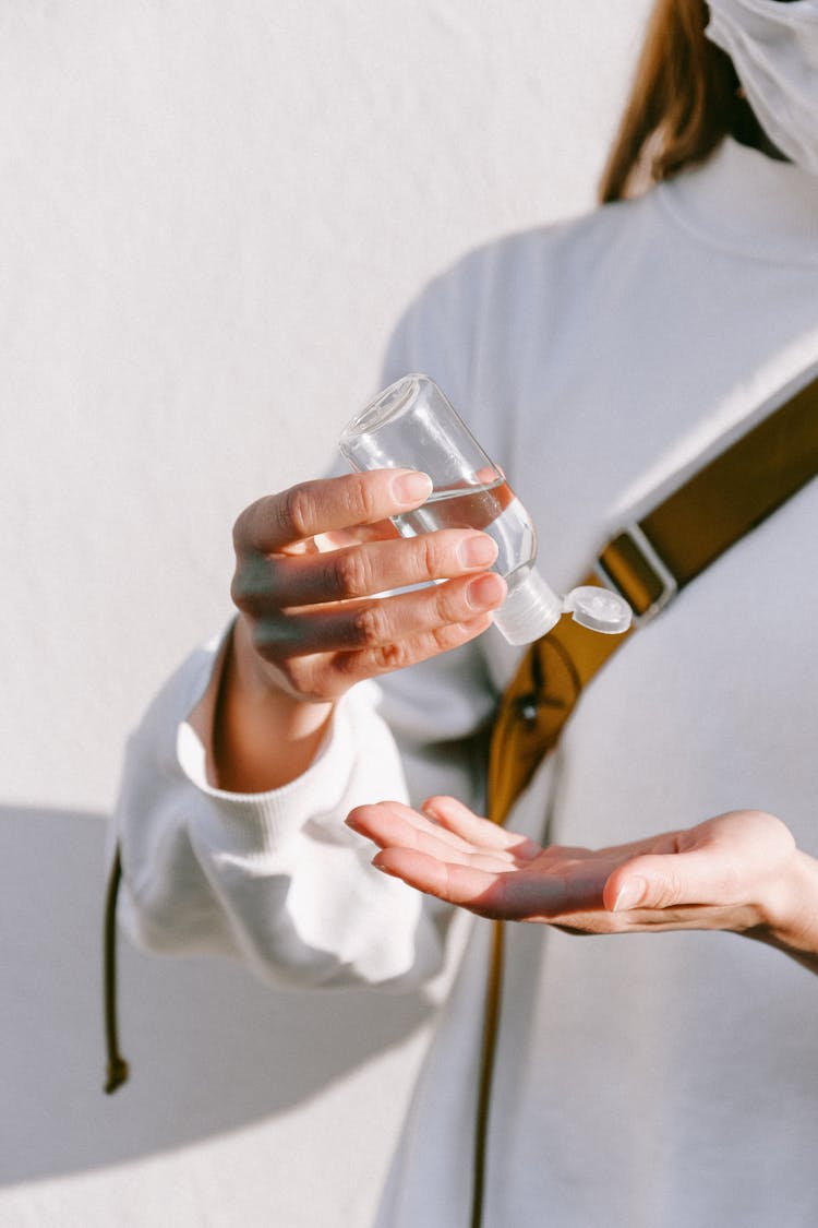 Person  In White Crew Neck Shirt Using Hand Sanitizer