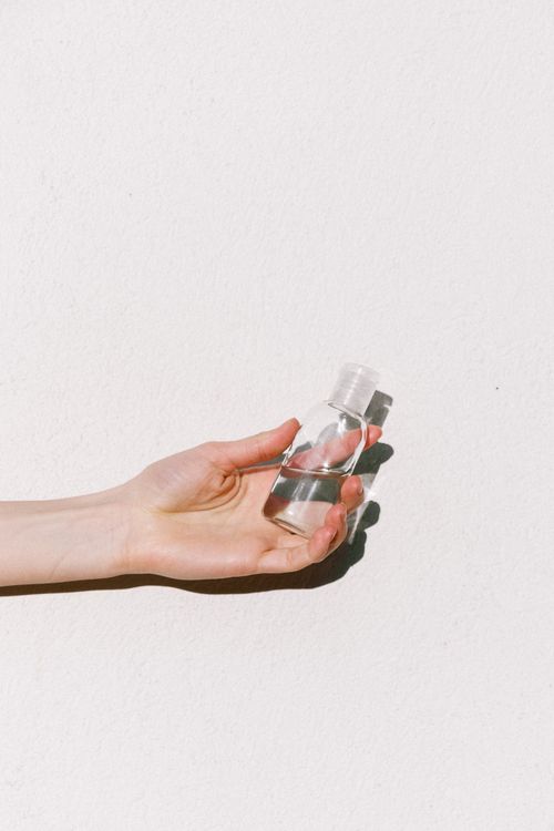 Free Close-up of a hand holding a transparent sanitizer bottle on a white background. Stock Photo