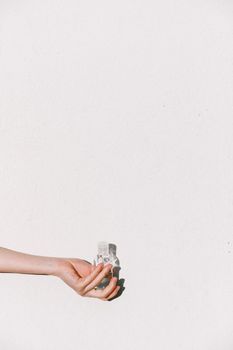 Minimalist image of a hand holding a sanitizer bottle against a white background, symbolizing hygiene and health.