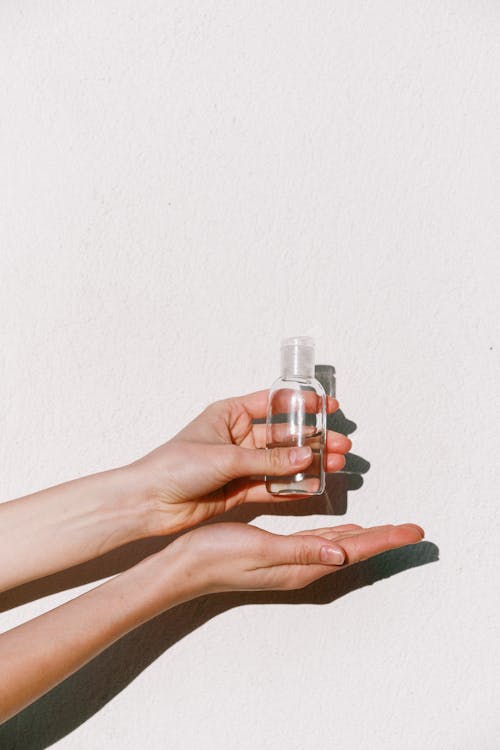 Person Holding Clear Glass Bottle