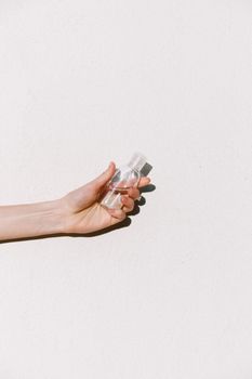 A person holding a transparent sanitizer bottle on a white background, emphasizing hygiene and health.