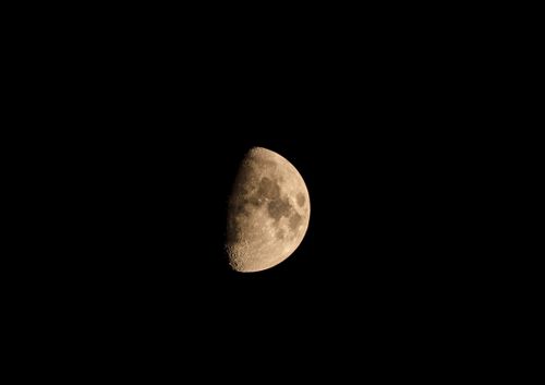 Free Detailed photograph of the moon in its first quarter phase set against a deep black sky. Stock Photo