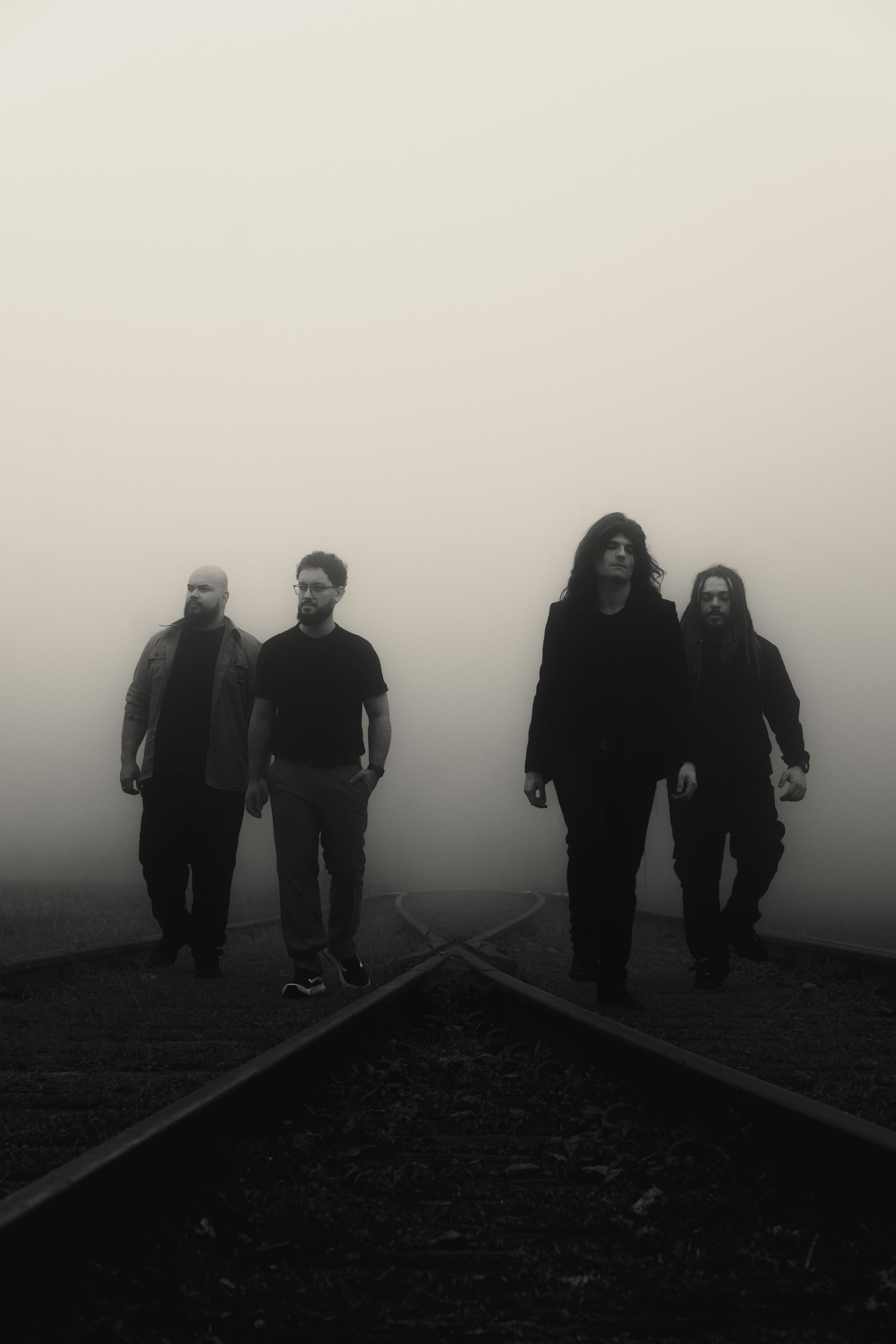 A music band walking on foggy railway tracks creating a dramatic, moody atmosphere.