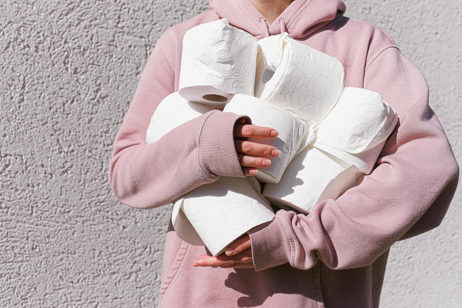 Woman in Pink Long Sleeve Hoodie Carrying Tissue Rolls