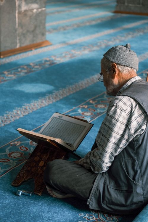 Free Elderly man reading in mosque interior, symbolizing wisdom and peace. Stock Photo