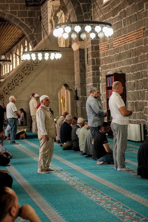 Free Men engaged in prayer inside a historic mosque with ornate interior design. Stock Photo