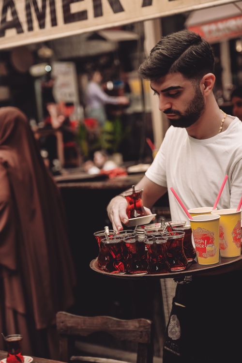 Free A young man serves traditional tea on a busy outdoor street food market. Stock Photo