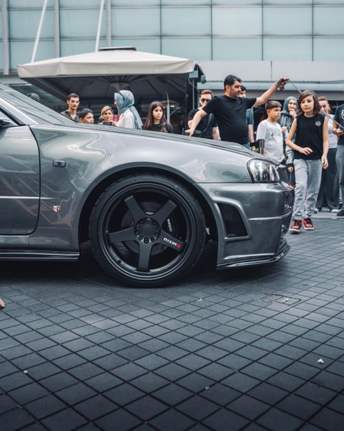 Free A sleek silver sports car surrounded by a crowd at an outdoor gathering in Ankara, Türkiye. Stock Photo