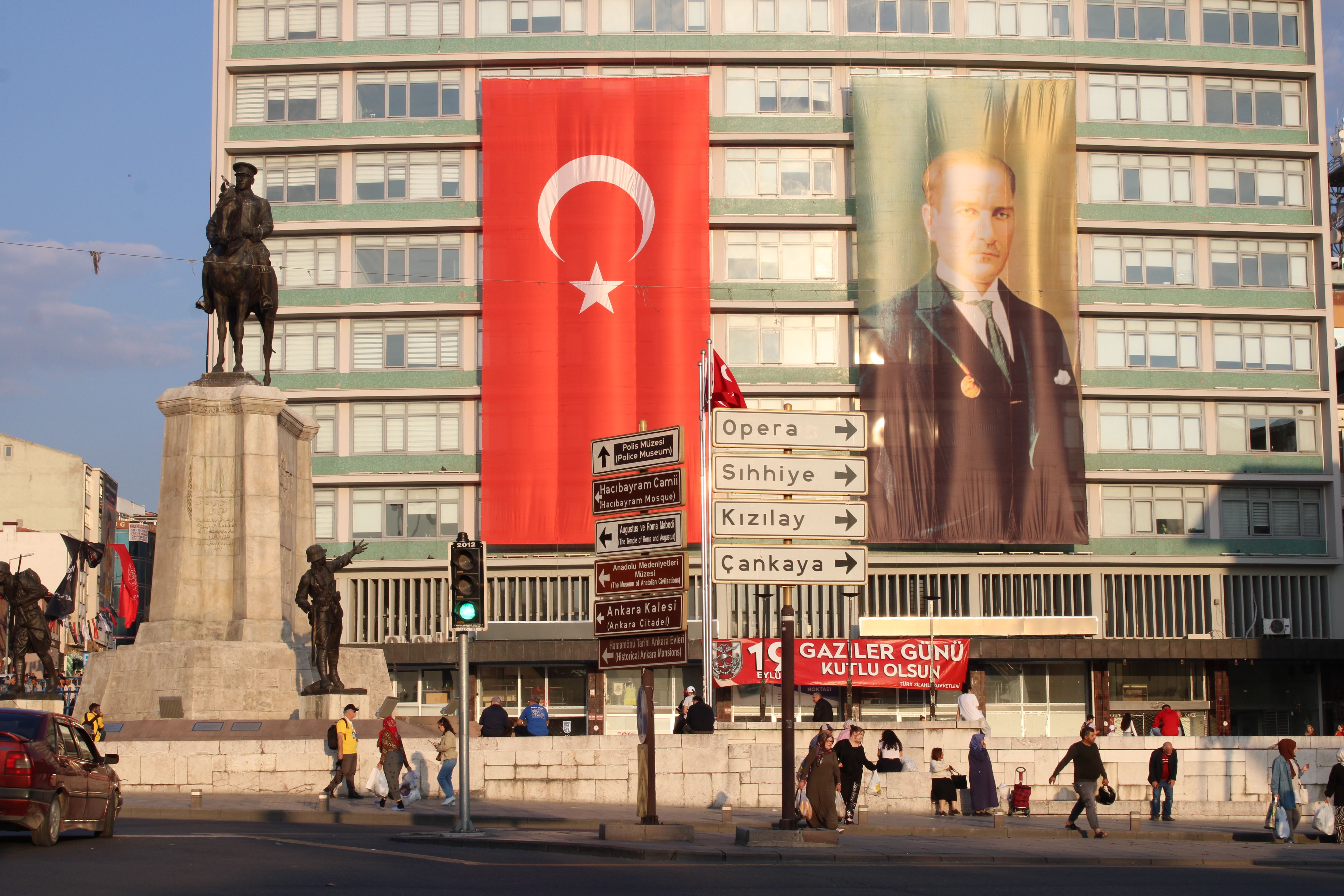 Ulus Square in Ankara featuring Atatürk statue, Turkish flag, and traffic signage at daytime.
