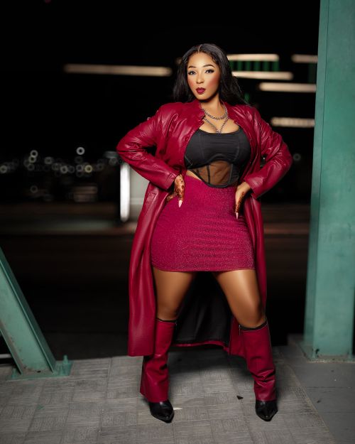 Free Stylish woman in red outfit posing confidently under urban lights at night. Stock Photo