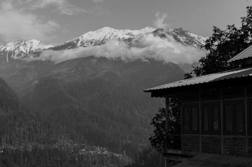 Free Serene black and white photo of snow-capped mountains and a rustic cabin. Stock Photo