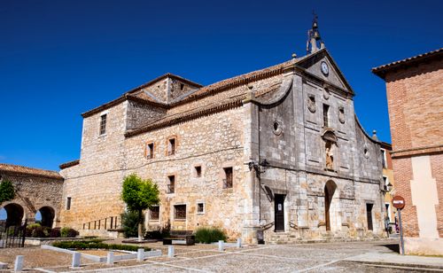 Free A charming historical stone church under a deep blue sky in Lerma, Spain. Stock Photo