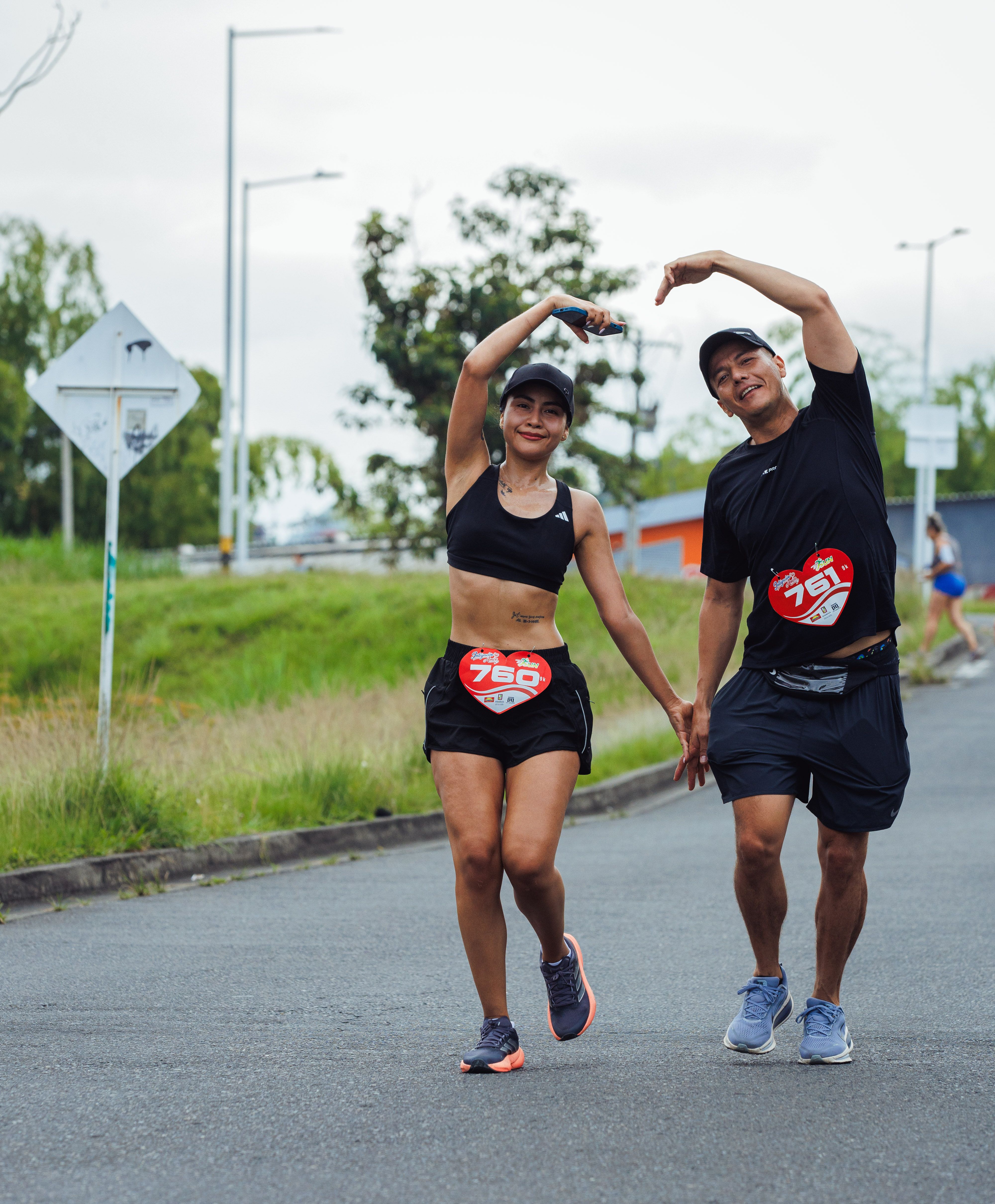 Couple enjoying a race event, smiling and making a heart gesture.