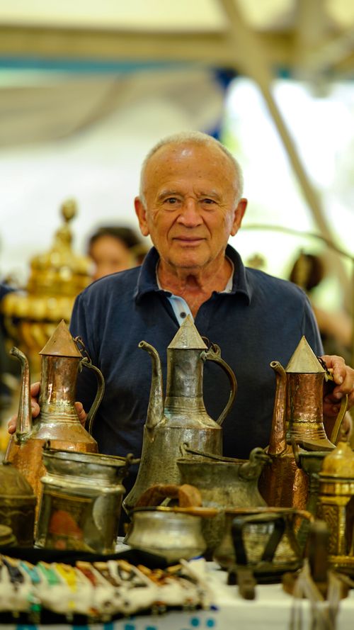 Free Senior vendor presenting an array of antique copperware at a market in Bursa. Stock Photo