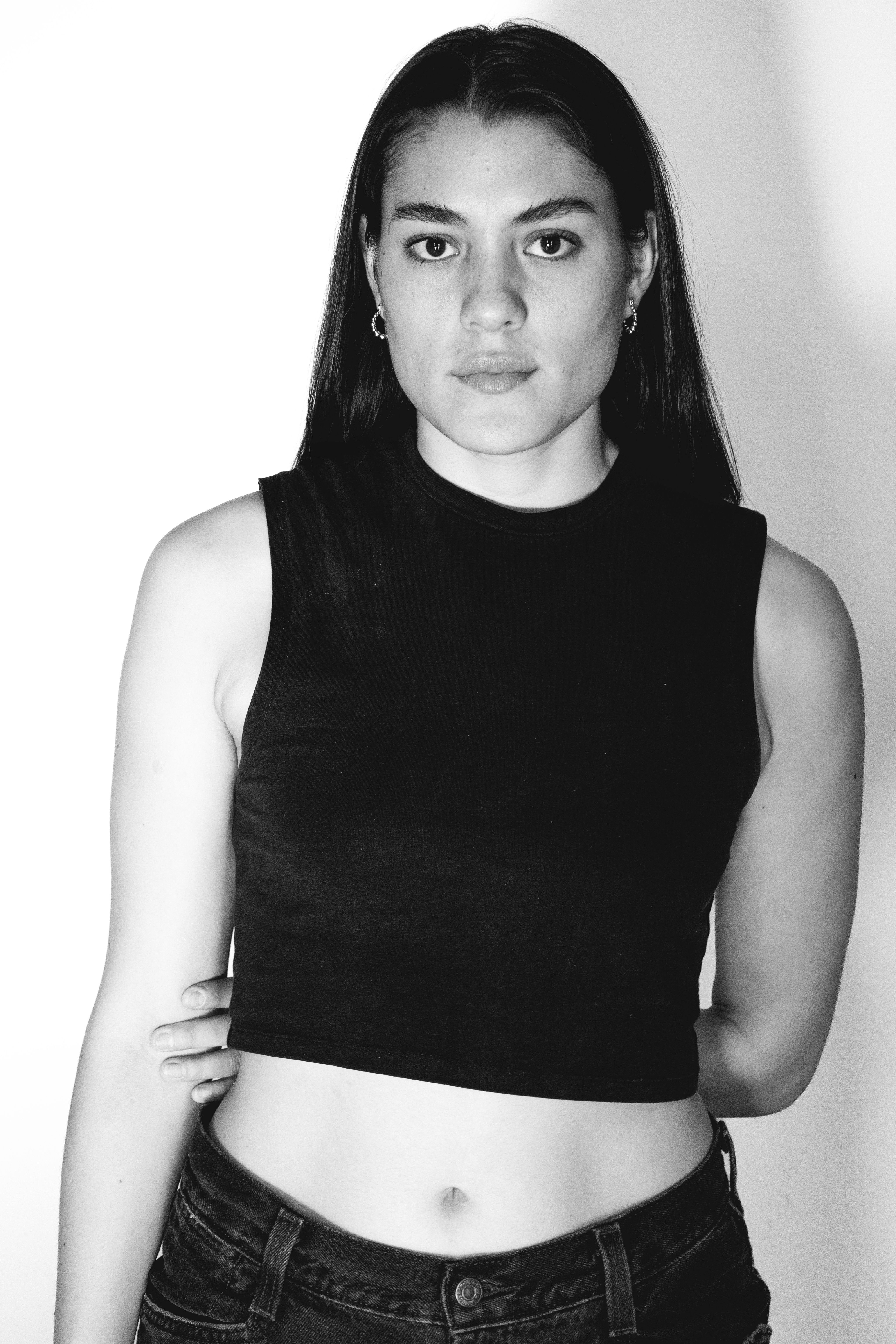 Elegant black and white portrait of a young woman standing confidently indoors.
