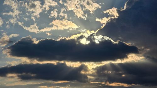 Free Beautiful sunset with dramatic clouds and sun rays breaking through, creating a serene natural scene. Stock Photo