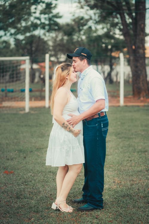 Free A loving couple shares an intimate moment outdoors, set against a lush green backdrop. Stock Photo