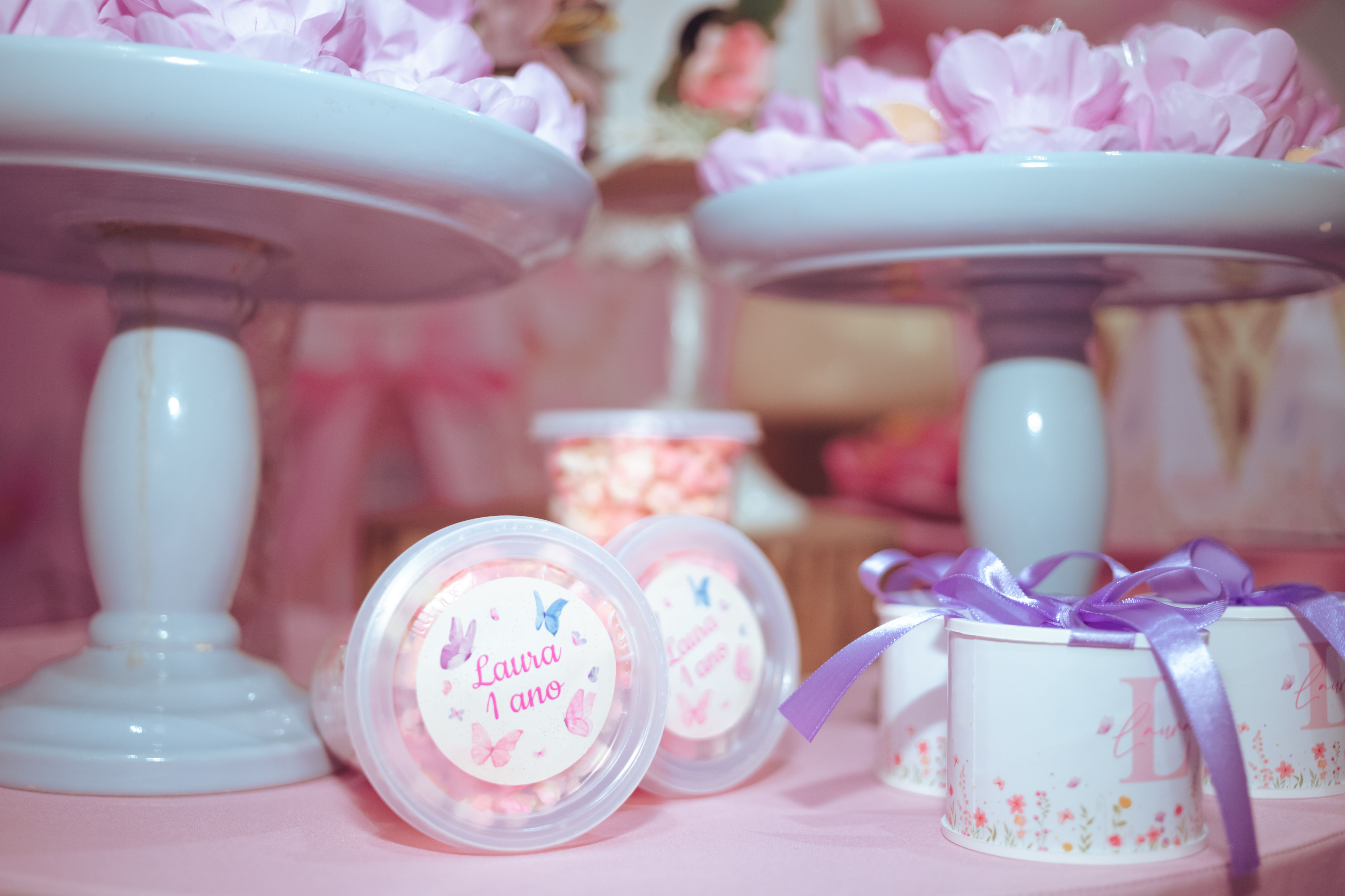 Charming pastel pink birthday party setup with decorated gift containers and floral accents.