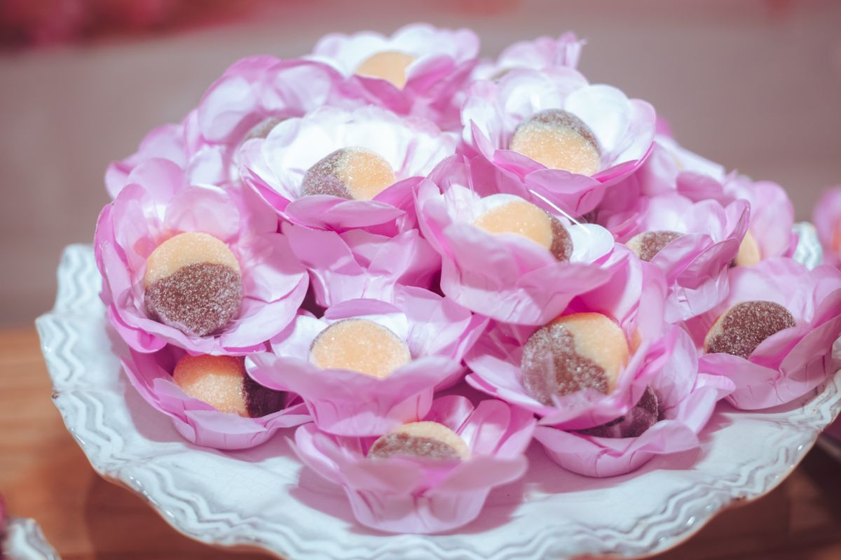 A close-up of assorted candies elegantly arranged in pink floral wrappers on a decorative plate.