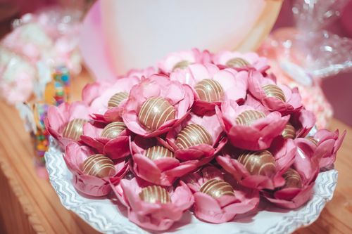 Free Close-up of chocolate candies arranged in pink floral wrappers on a decorative plate. Stock Photo