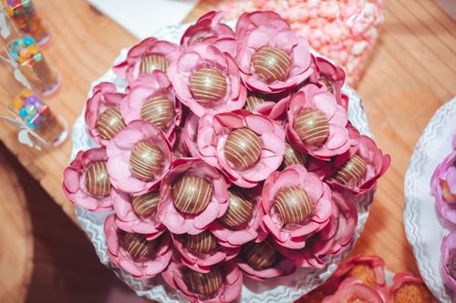 Free Elegant display of chocolate truffles in decorative pink flower wrappers, perfect for celebrations. Stock Photo