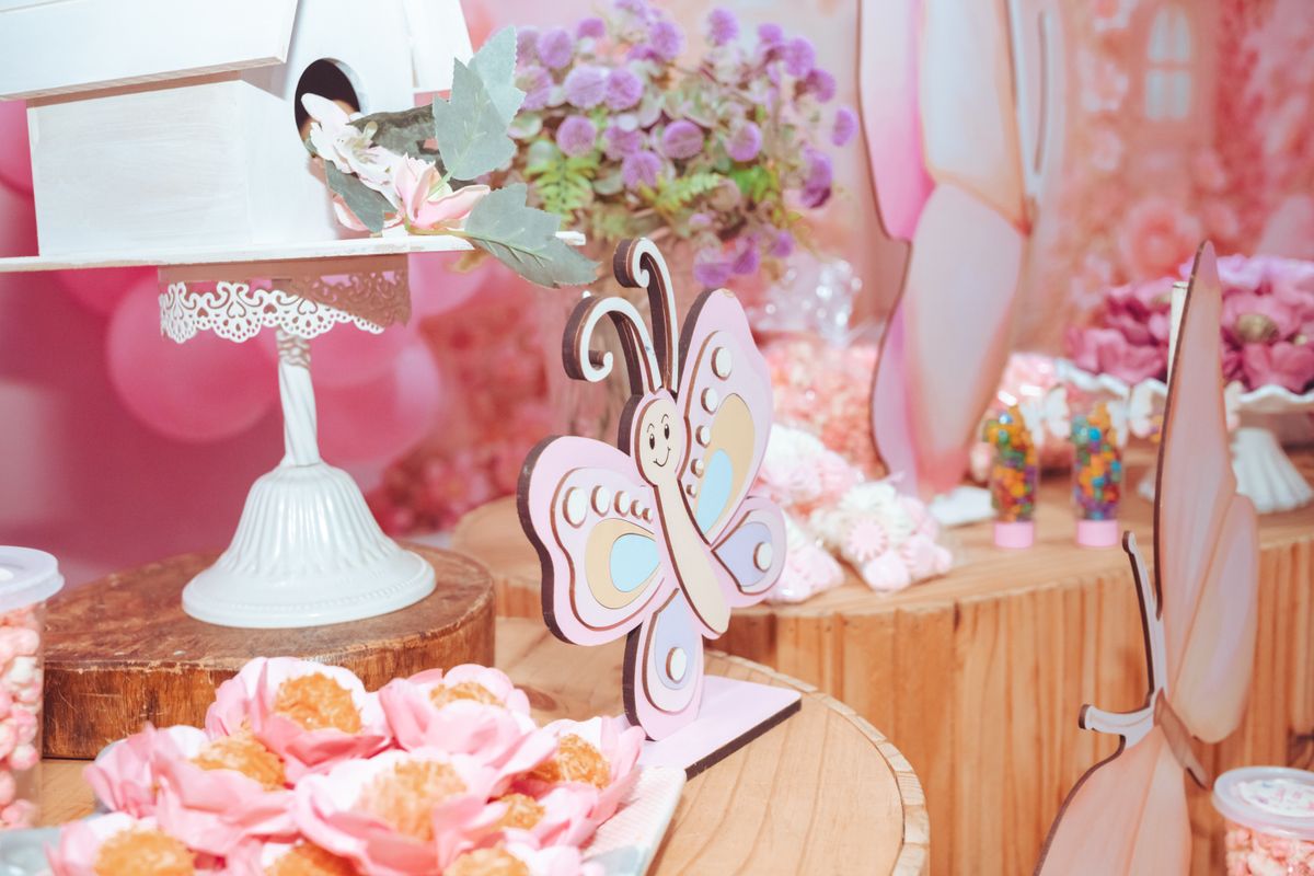 A delightful pink party table setup with butterfly decorations, flowers, and sweet treats. Stock Photo.