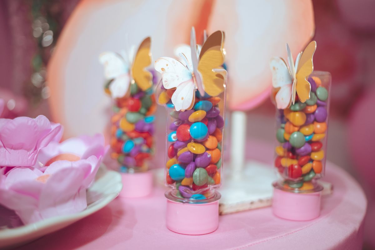 Playful display of colorful candies in jars with butterfly decorations on a pastel table setting.