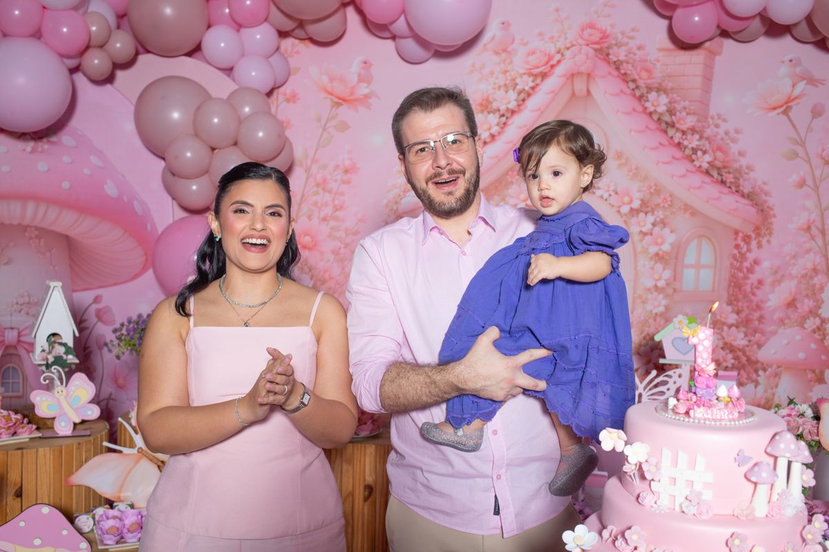 Family celebrating their baby's first birthday with cake and decorations. Stock Photo.