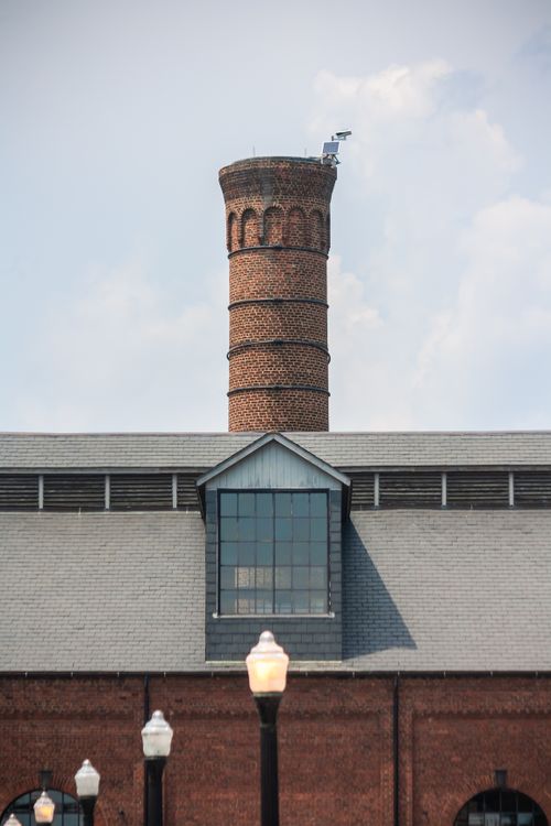 Free Old red brick chimney stands over industrial building in Richmond, Virginia, USA. Stock Photo