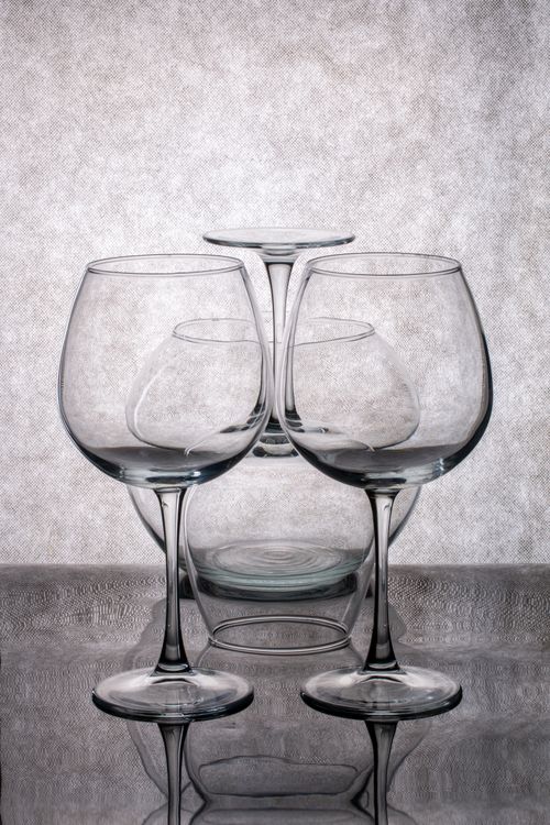 Free Artistic arrangement of wine glasses on a reflective surface, showcasing elegance and symmetry. Stock Photo