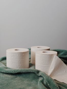 Three toilet paper rolls on plush fabric, symbolizing hygiene and essentials.