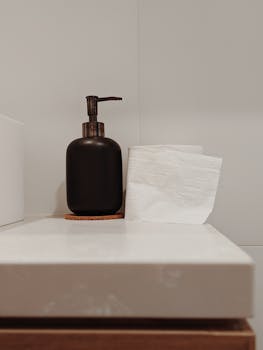A clean and minimalist bathroom setup showing a soap dispenser and toilet paper.