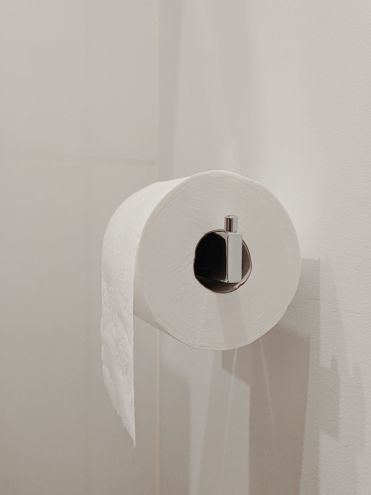 Large white roll on a wall holder against a plain white wall