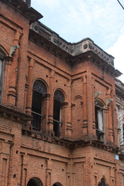 Free Close-up of historic brick building facade with decorative arches and windows under a blue sky. Stock Photo