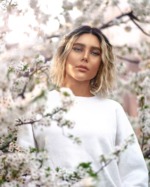 Woman surrounded by blooming spring flowers, capturing serene beauty outdoors.
