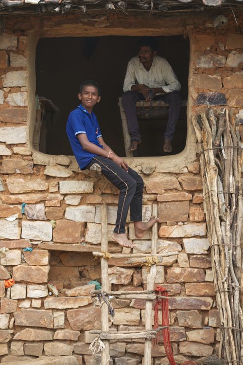 Free A boy and man in traditional rural Indian setting on a stone wall. Stock Photo