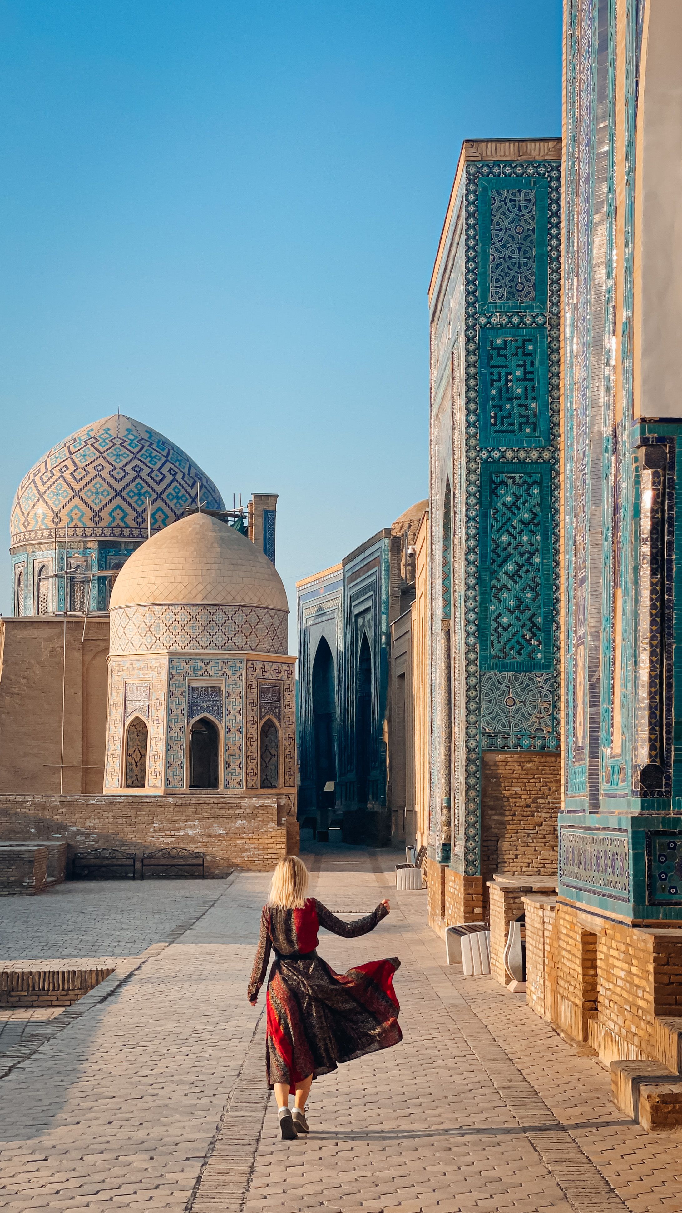 Free A woman walks along the ancient Shah-i-Zinda necropolis in Samarqand, showcasing stunning Islamic architecture. Stock Photo