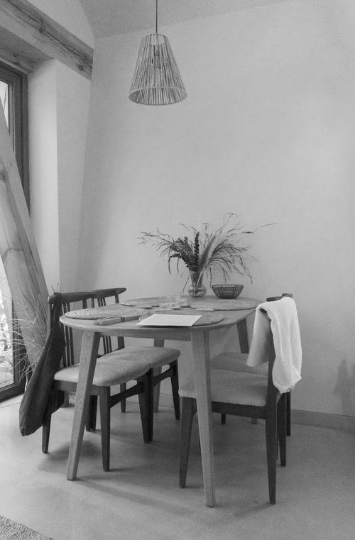 Free Black and white photo of a minimalist dining setup with natural light and wooden furniture. Stock Photo
