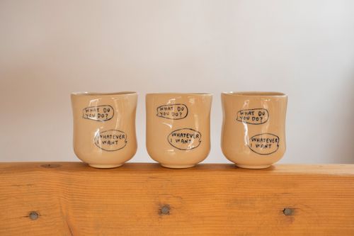 Free Three ceramic cups with playful 'What do you do? Whatever I want' text design on a wooden surface. Stock Photo