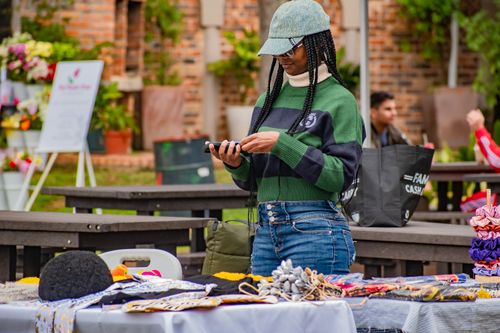 Free A young woman sets up her stall at an outdoor craft market in Malkerns, Eswatini. Stock Photo